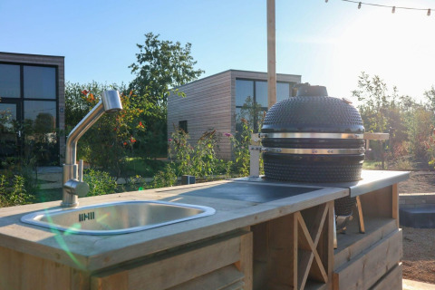 Cucina all'aperto con lavello e barbecue a Tiny House 4, Marina Strandbad, Paesi Bassi, al tramonto.