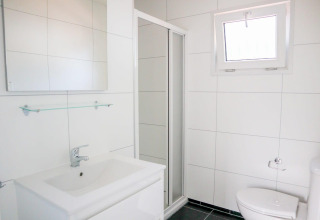 Moderne badkamer in Cube la Mer 4 bij Marina Strandbad, Nederland, met douche en witte tegels.