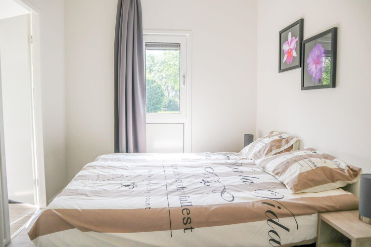 Dormitorio luminoso en Cube la Mer 4, Marina Strandbad, Países Bajos, con cama doble y cuadros de flores en la pared.