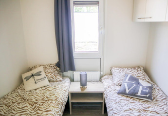 Two single beds with animal print bedding, decorative cushions and a small table at Cube la Mer 4, Marina Strandbad.