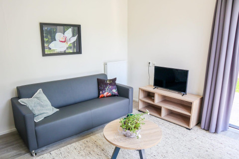Modernes Wohnzimmer in Cube la Mer 4, Marina Strandbad, Niederlande, mit Sofa, Fernseher und Tisch.