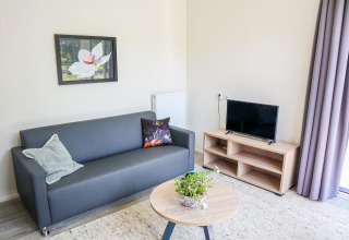 Moderne zithoek in Cube la Mer 4 aan Marina Strandbad, Nederland, met bank, tv en salontafel.