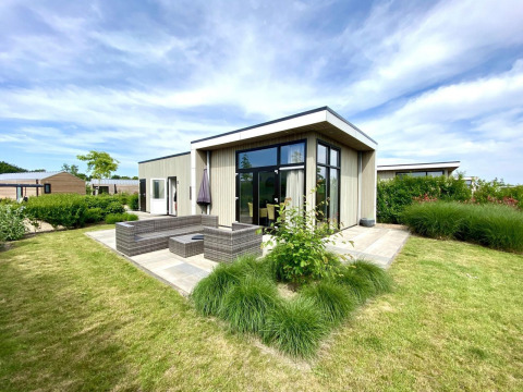 Cube la Mer 4 lodge au Marina Strandbad aux Pays-Bas, architecture moderne, terrasse et beau jardin verdoyant.