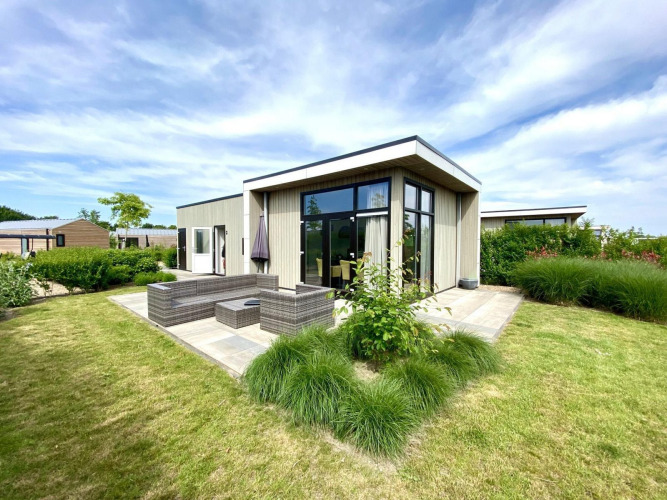 Cube la Mer 4 lodge en Marina Strandbad, Países Bajos, con diseño moderno, terraza y amplio jardín verde.