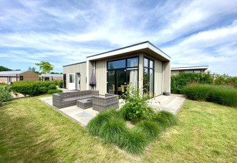 Cube la Mer 4 lodge au Marina Strandbad aux Pays-Bas, architecture moderne, terrasse et beau jardin verdoyant.