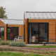 Moderne Wellness Lodge 2 med træfacade, store vinduer og grøn have i naturskønne omgivelser.