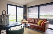 Modernes Wohnzimmer in der Wellness Lodge 2 im Marina Strandbad, Niederlande, mit Sofa und Fenstern.