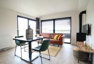 Moderne woonkamer in Wellness Lodge 2 bij Marina Strandbad, Nederland, met leren bank en eettafel.