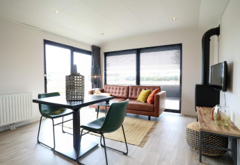 Moderne stue i Wellness Lodge 2, Marina Strandbad, Holland, med lædersofa, spisebord og store vinduer.
