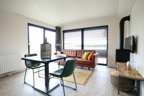 Modernes Wohnzimmer in der Wellness Lodge 2, Marina Strandbad, Niederlande, mit Ledersofa und Esstisch.