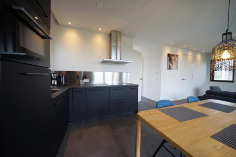 Cocina moderna y comedor en una cabaña Modus 4 en Marina Strandbad, Países Bajos, con muebles oscuros.