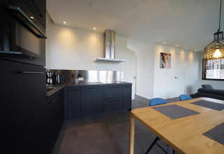 Cocina moderna y comedor en una cabaña Modus 4 en Marina Strandbad, Países Bajos, con muebles oscuros.