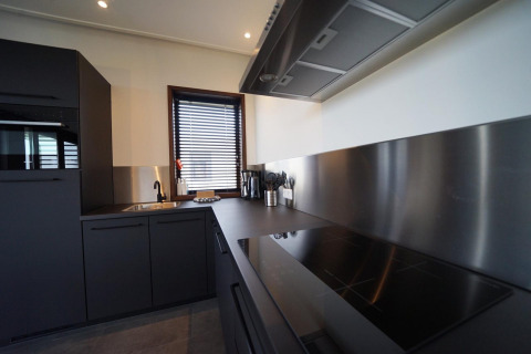 Interior de cocina moderna en la cabaña Modus 4 en Marina Strandbad, Países Bajos, con gabinetes negros y acero.