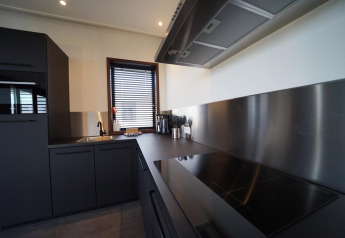 Modern kitchen interior of Modus 4 lodge at Marina Strandbad, Netherlands, with black cabinets and steel surfaces.