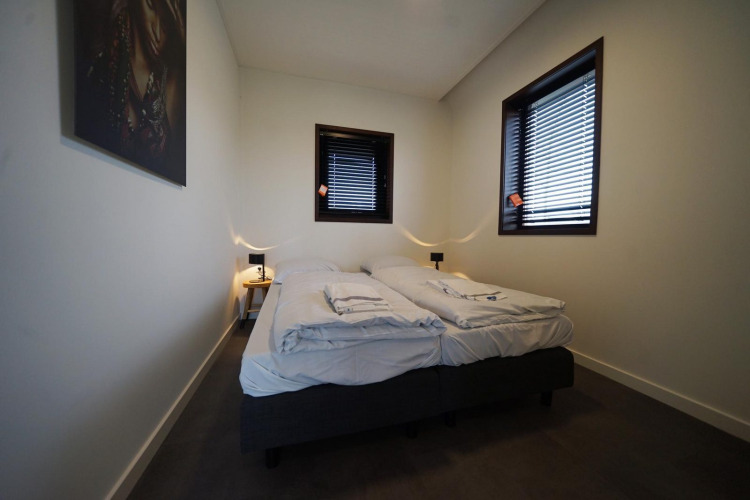 Moderne slaapkamer met twee eenpersoonsbedden, jaloezieën en minimalistische inrichting in Modus 4, Marina Strandbad.