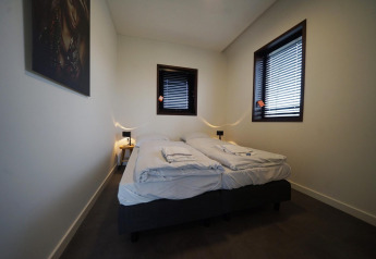 Moderne slaapkamer met twee eenpersoonsbedden, jaloezieën en minimalistische inrichting in Modus 4, Marina Strandbad.