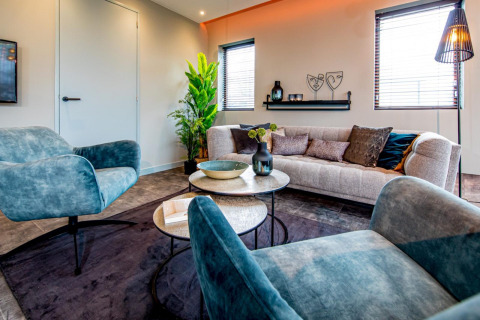 Salon moderne du Modus 4 à Marina Strandbad, Pays-Bas, avec fauteuils bleus, canapé et plante verte.