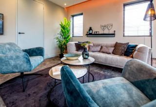 Salón moderno en Modus 4, Marina Strandbad, Países Bajos, con sillones azules, sofá y plantas verdes.