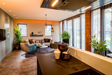 Moderne leefruimte in lodge Modus 4 bij Marina Strandbad, Nederland, met grote ramen en groene planten.