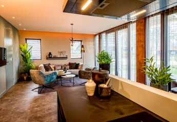 Salon moderne du lodge Modus 4 à Marina Strandbad, Pays-Bas, avec grandes baies vitrées et plantes vertes.