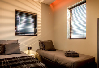 Twee enkele bedden en hedendaagse inrichting in Modus 4 lodge aan Marina Strandbad in Nederland, zoninval.