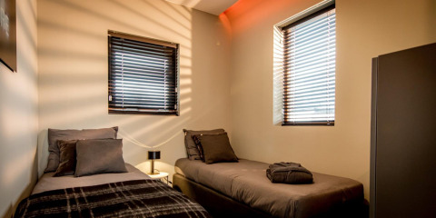 To enkeltsenge og moderne indretning på Modus 4 lodge ved Marina Strandbad i Holland, sollys filtrerer gennem gardiner.