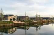 Modernos lodges junto al lago en Hackfort 6, De Kraaijenbergse Plassen, Países Bajos, con reflejos en el agua.