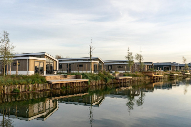 Modernos lodges junto al lago en Hackfort 6, De Kraaijenbergse Plassen, Países Bajos, con reflejos en el agua.