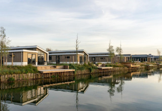 Lodges modernes au bord du lac à Hackfort 6, De Kraaijenbergse Plassen aux Pays-Bas, reflétés dans l’eau calme.