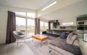 Moderne woonkamer in Hackfort 6 lodge aan De Kraaijenbergse Plassen, Nederland, met grote ramen en sofa.