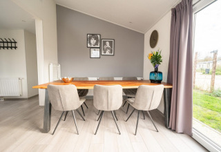Espace repas moderne avec table en bois, chaises grises et grande fenêtre au Hackfort 6, De Kraaijenbergse Plassen.