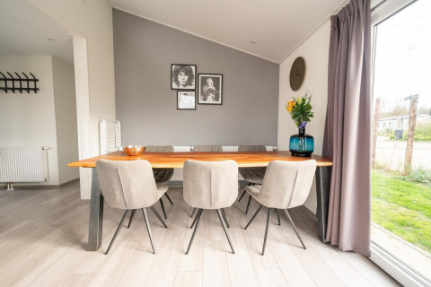 Comedor con mesa de madera, sillas grises y ventanales en Hackfort 6 de De Kraaijenbergse Plassen, Países Bajos.