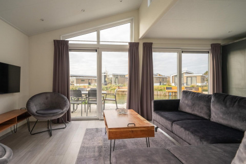 Salon lumineux du lodge Hackfort 6 aux Kraaijenbergse Plassen, Pays-Bas, avec mobilier moderne et grandes fenêtres.