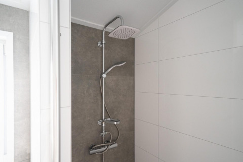 Douche moderne dans la salle de bain du Hackfort 6 à De Kraaijenbergse Plassen, Pays-Bas, avec carrelage blanc.