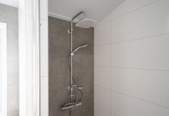 Modern shower in the bathroom of Hackfort 6 at De Kraaijenbergse Plassen, Netherlands, with white tiles.