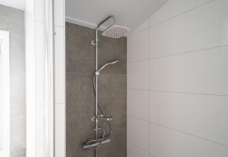 Ducha moderna en el baño de Hackfort 6 en De Kraaijenbergse Plassen, Países Bajos, con azulejos blancos.