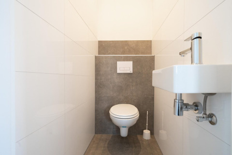 Toilettes minimalistes avec WC suspendu et petit lavabo à Hackfort 6, De Kraaijenbergse Plassen, Pays-Bas.