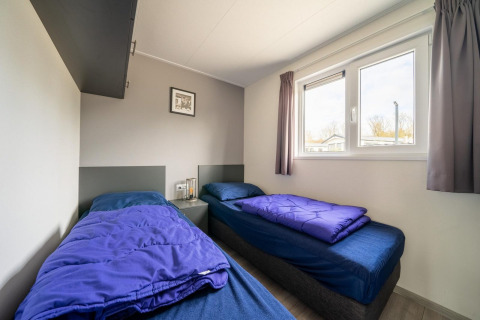 Deux lits simples avec literie bleue dans une chambre du Hackfort 6 au De Kraaijenbergse Plassen, Pays-Bas.