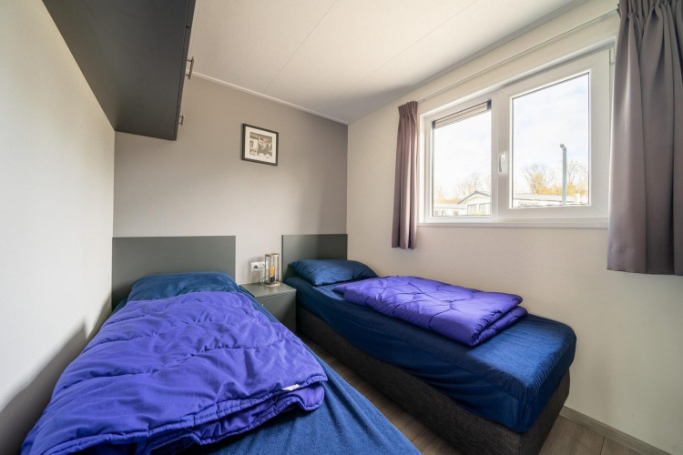 Dos camas individuales con ropa de cama azul en una habitación de Hackfort 6 en De Kraaijenbergse Plassen, Países Bajos.