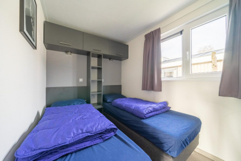Chambre lumineuse avec deux lits simples et du linge bleu à Hackfort 6, De Kraaijenbergse Plassen, Pays-Bas.