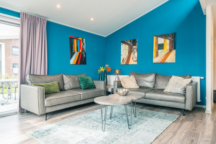 Sala luminosa en la cabaña Hackfort 8, De Kraaijenbergse Plassen, Países Bajos, con arte y muebles modernos.