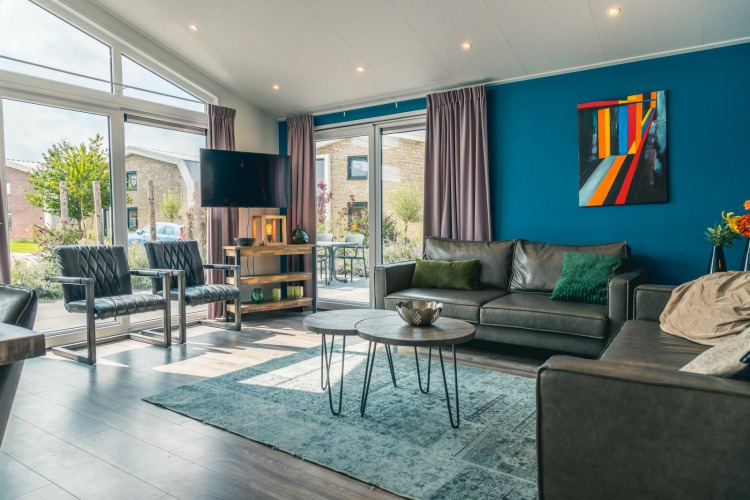 Sala de estar moderna en la cabaña Hackfort 8 en De Kraaijenbergse Plassen, Países Bajos, con grandes ventanales.