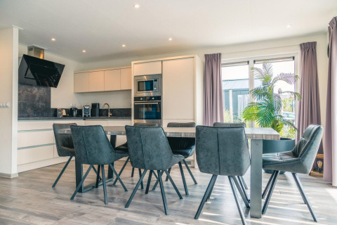 Moderne keuken en eetruimte in Hackfort 8, De Kraaijenbergse Plassen, Nederland, met grijze stoelen.