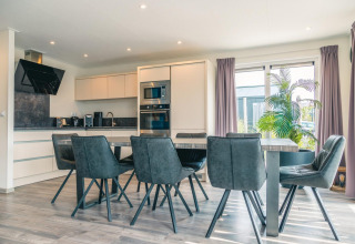 Cuisine et salle à manger modernes au Hackfort 8, De Kraaijenbergse Plassen, Pays-Bas, avec chaises grises.