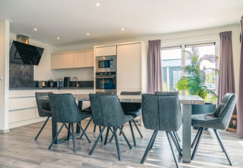 Cocina y comedor modernos en Hackfort 8, De Kraaijenbergse Plassen, Países Bajos, con sillas grises.