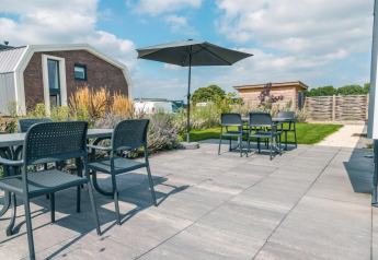 Sonnige Terrasse mit Gartenmöbeln und Sonnenschirm bei Hackfort 8, De Kraaijenbergse Plassen, Niederlande.