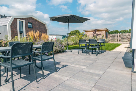 Buitenterras met tafels, stoelen en parasol bij Hackfort 8, De Kraaijenbergse Plassen, Nederland.