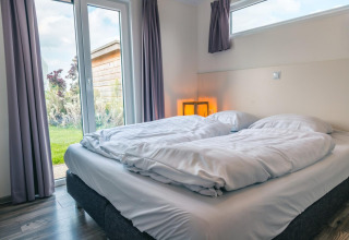 Moderne slaapkamer in Hackfort 8, De Kraaijenbergse Plassen, Nederland, met dubbel bed en tuinzicht.