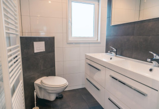 Moderne badkamer bij Hackfort 8, De Kraaijenbergse Plassen, Nederland, met dubbele wasbak en hangtoilet.