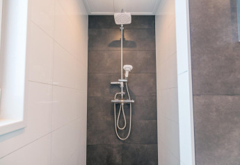 Moderne Dusche in der Hackfort 8 Lodge bei De Kraaijenbergse Plassen, Niederlande, mit schwarzen Fliesen.